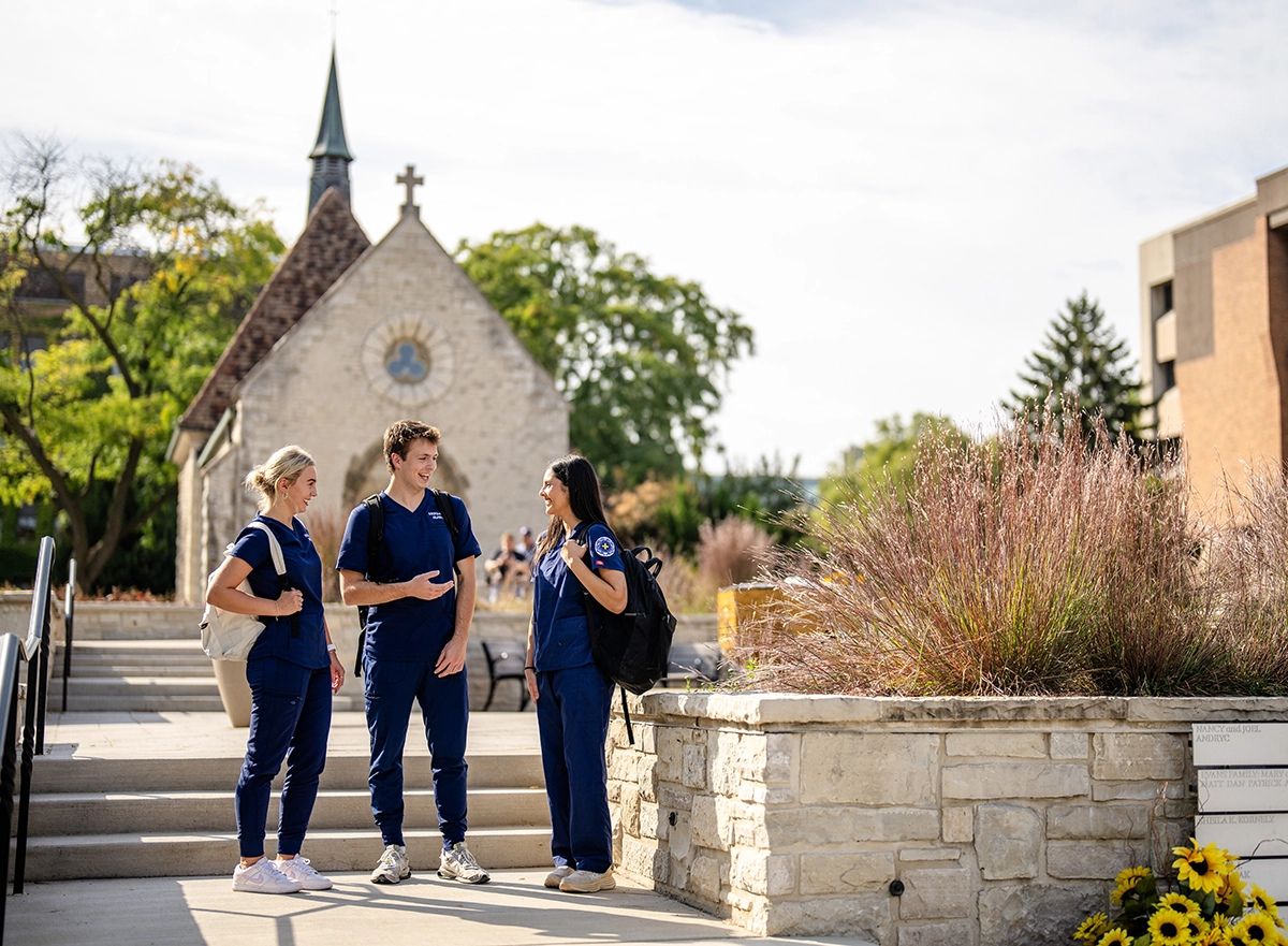 Three nursing students in front of chapel