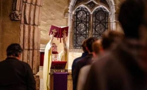 Priest raising a book up in church