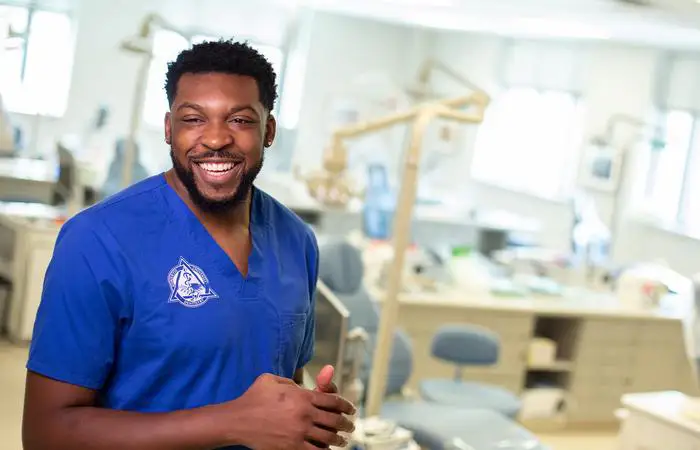 student dentist poses in front of dentist chair