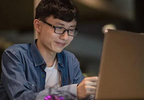 student looks at computer confident and happy