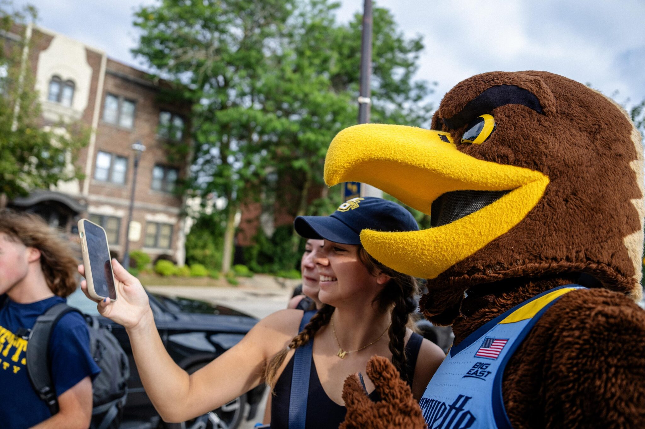 Student taking a selfie with Iggy, the Marquette Athletics mascot